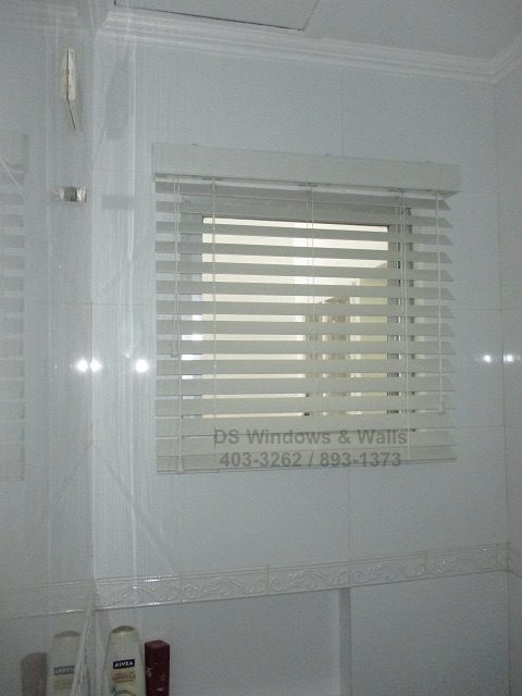 Shallow window depth outside mounted white wood blinds.